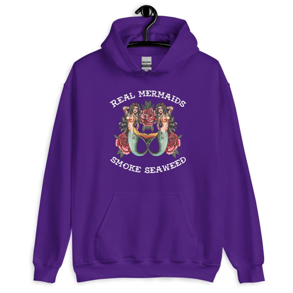 Purple hoodie sweatshirt with image of 2 mermaids and the text 'Real mermaids smoke seaweed' printed on the front.