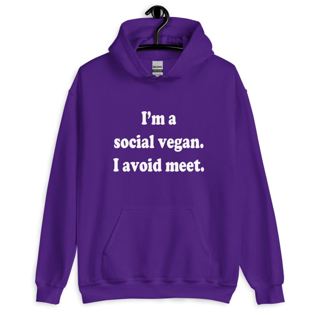 Purple hoodie sweatshirt with the pun phrase 'I'm a social vegan. I avoid meet.' printed on the front.
