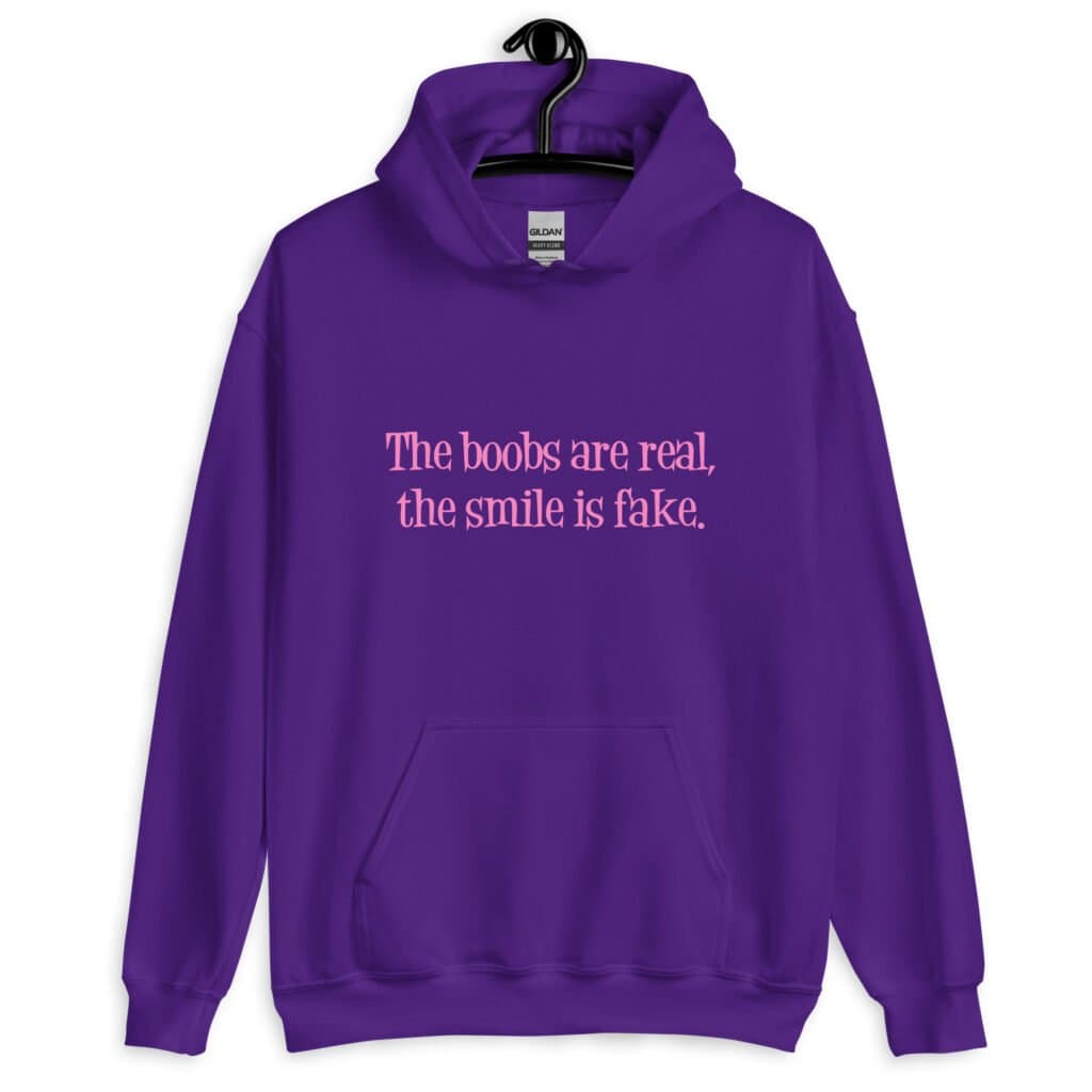 Purple hoodie sweatshirt with the text 'The boobs are real, the smile is fake.' printed in pink on the front.