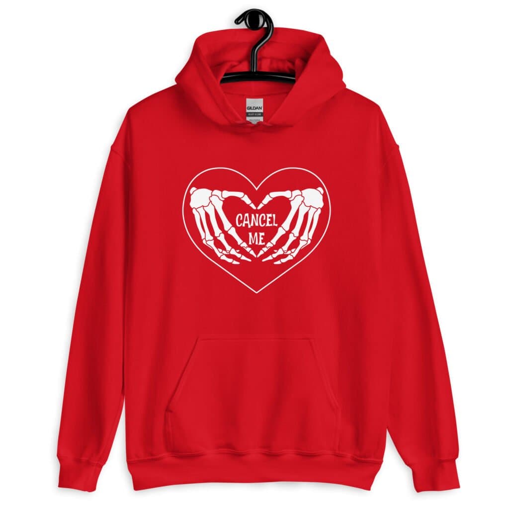 Red hoodie sweatshirt with a heart and skeleton hands making a heart shape printed on the front. The words 'Cancel Me' are inside of the heart.
