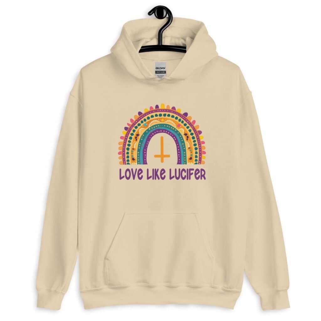 Sand color hoodie sweatshirt with an image of a boho style rainbow. There is an upside down cross in the center arch of the rainbow and the text 'Love like Lucifer' printed under. The graphics are printed on the front.