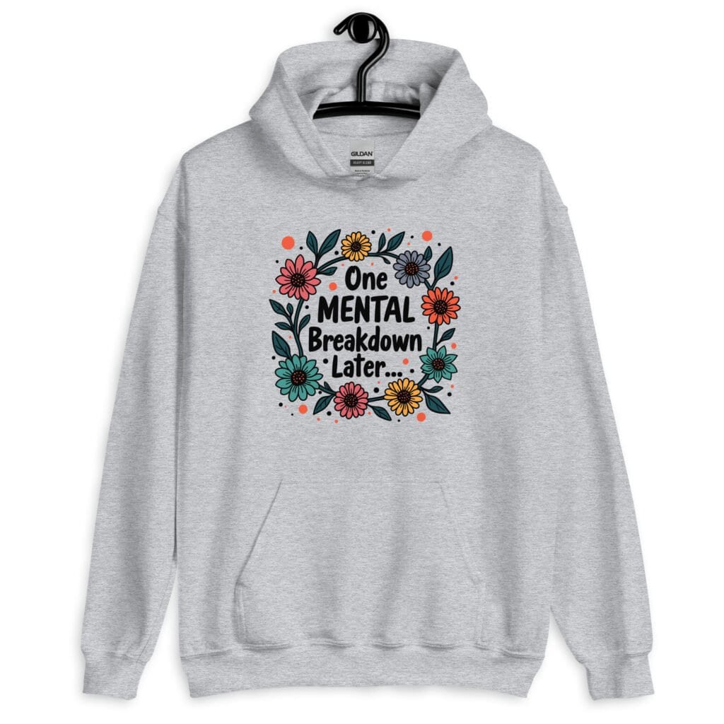 Sport grey hoodie sweatshirt with a multi color floral wreath design printed on the front. The words 'One mental breakdown later...' are printed in the center of the wreath.