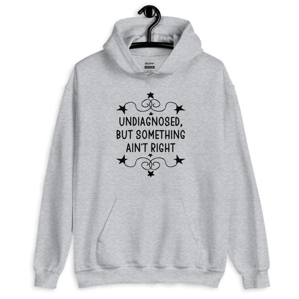 Sport grey hoodie sweatshirt with the phrase 'Undiagnosed, but something ain't right 'printed on the front. The text is black and has a star graphic embellishment around the words.