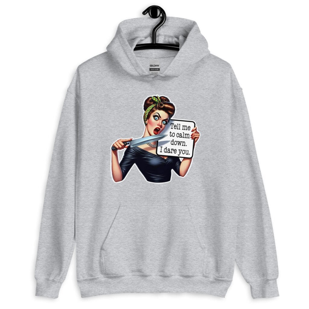 Sport grey hoodie sweatshirt that has a graphic of an angry looking retro woman holding a knife and a sign. The sign says 'Tell me to calm down. I dare you.' The graphic is printed on the front of the hoodie.