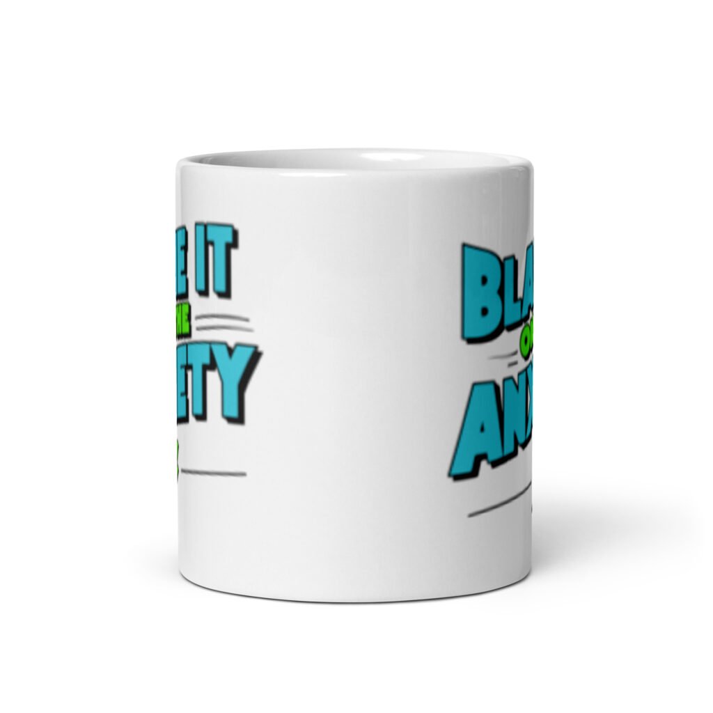 White ceramic mug with the phrase 'Blame is on the anxiety' printed on both sides of the mug. The graphics are bold and in aqua and lime green.