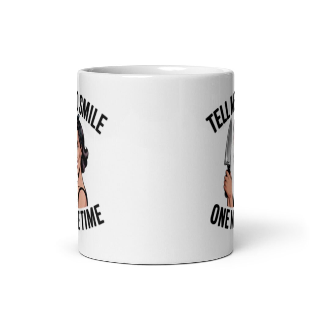 White ceramic mug with graphic of a woman holding a knife and the phrase 'Tell me to smile one more time' printed on both sides.