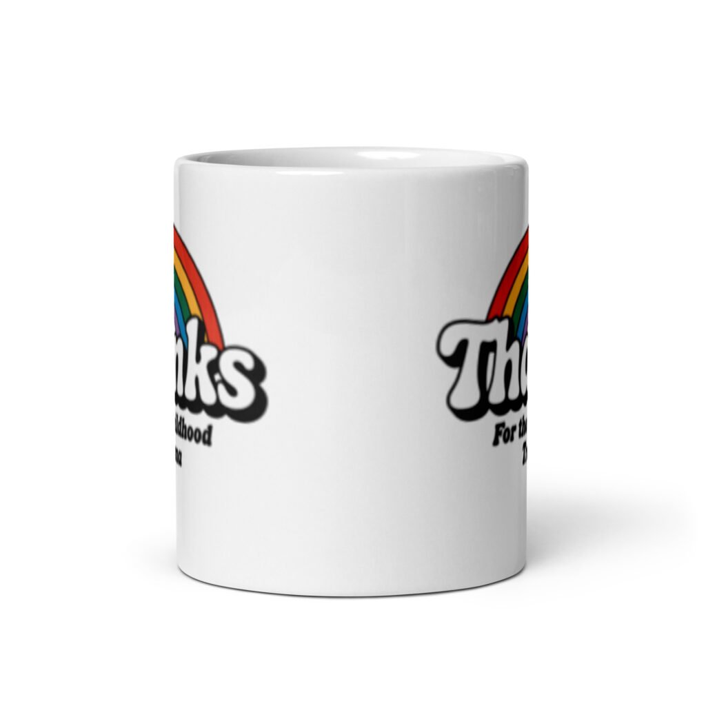 White ceramic mug with an image of a rainbow and the words 'Thanks for the childhood trauma' printed on both sides. The word Thanks is large and the rest of the words are smaller under.