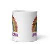 White ceramic mug with an image of a boho style rainbow. There is an upside down cross in the center arch of the rainbow and the text 'Love like Lucifer' printed under. The graphics are printed on both sides of the mug.