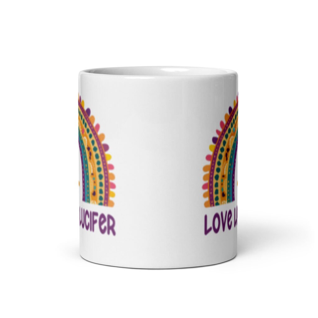 White ceramic mug with an image of a boho style rainbow. There is an upside down cross in the center arch of the rainbow and the text 'Love like Lucifer' printed under. The graphics are printed on both sides of the mug.