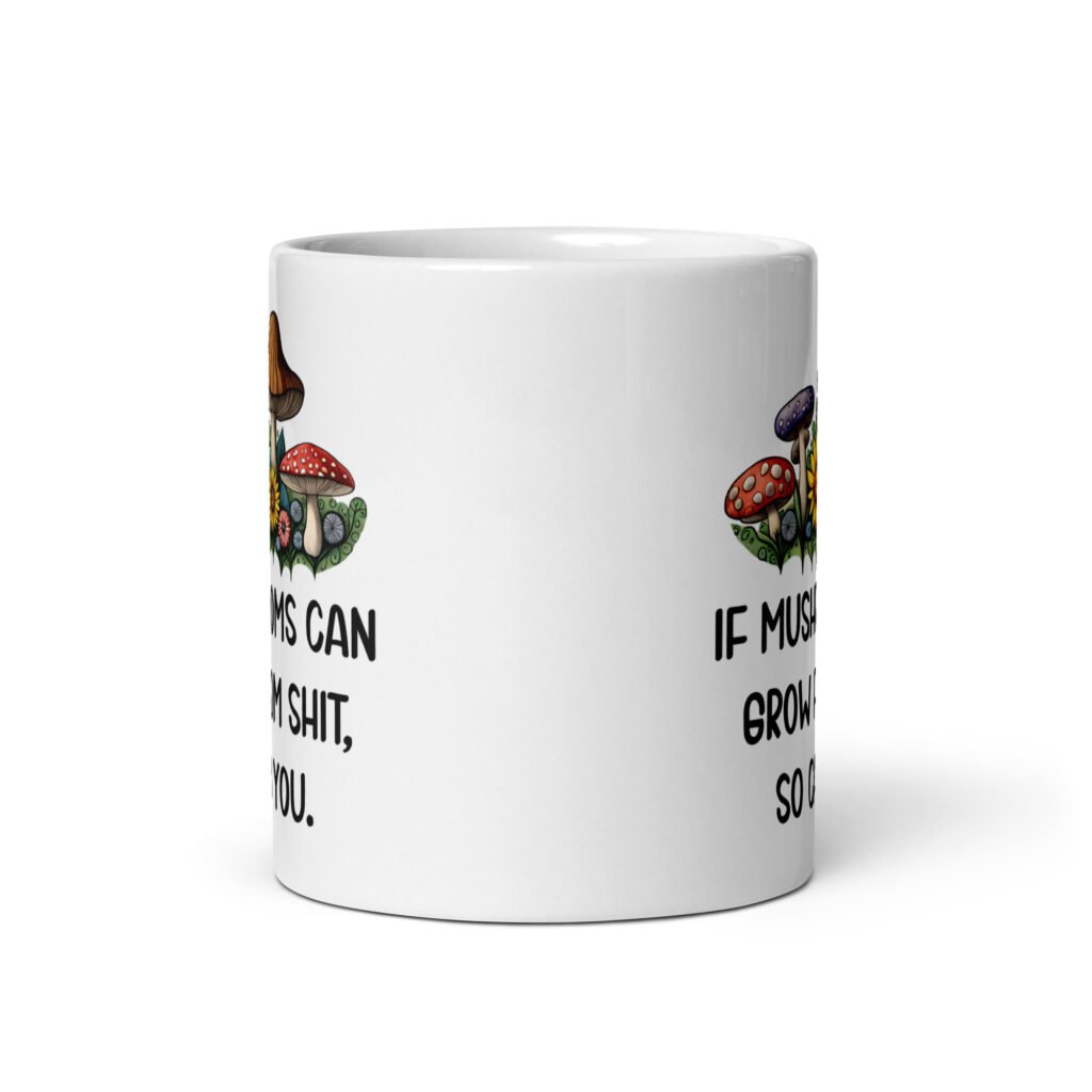 White ceramic coffee mug with images of mushrooms and the text 'If mushrooms can grow from shit so can you' printed on both sides.