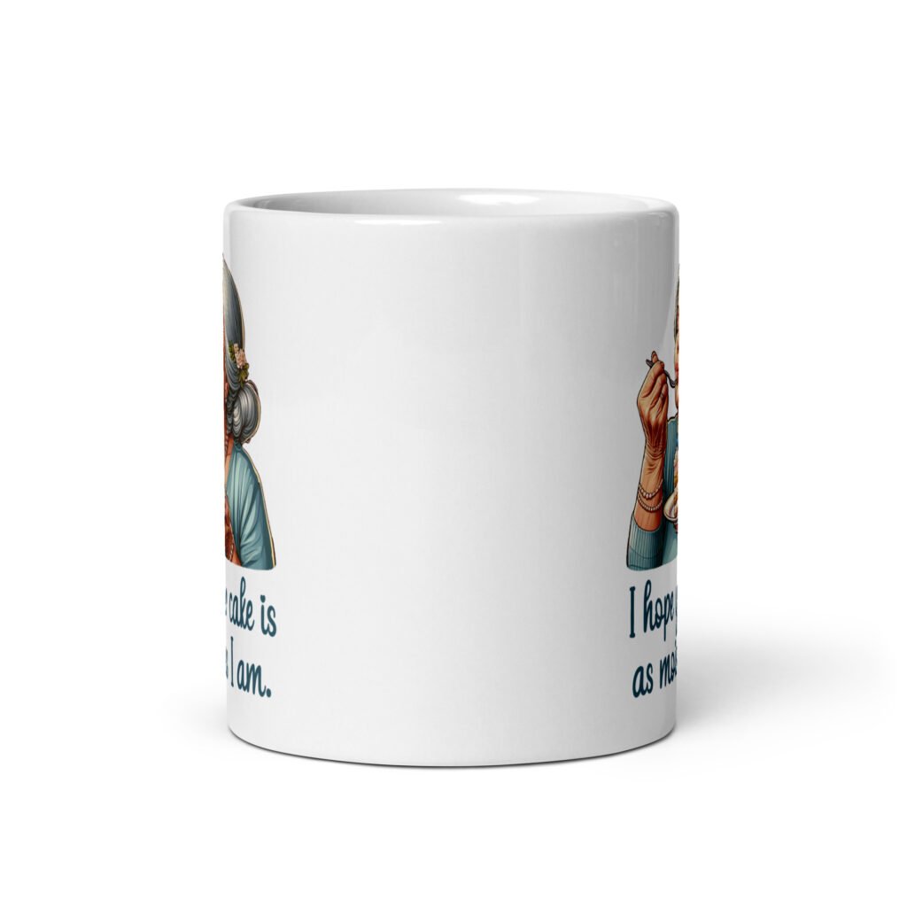 White ceramic coffee mug with an image of grey haired older woman enjoying a bite of a piece of cake with the words 'I hope your cake is as moist as I am' printed on both sides.