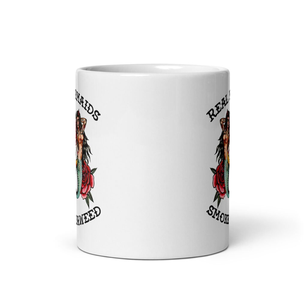 White ceramic mug with image of 2 mermaids and the text 'Real mermaids smoke seaweed' printed on both sides.