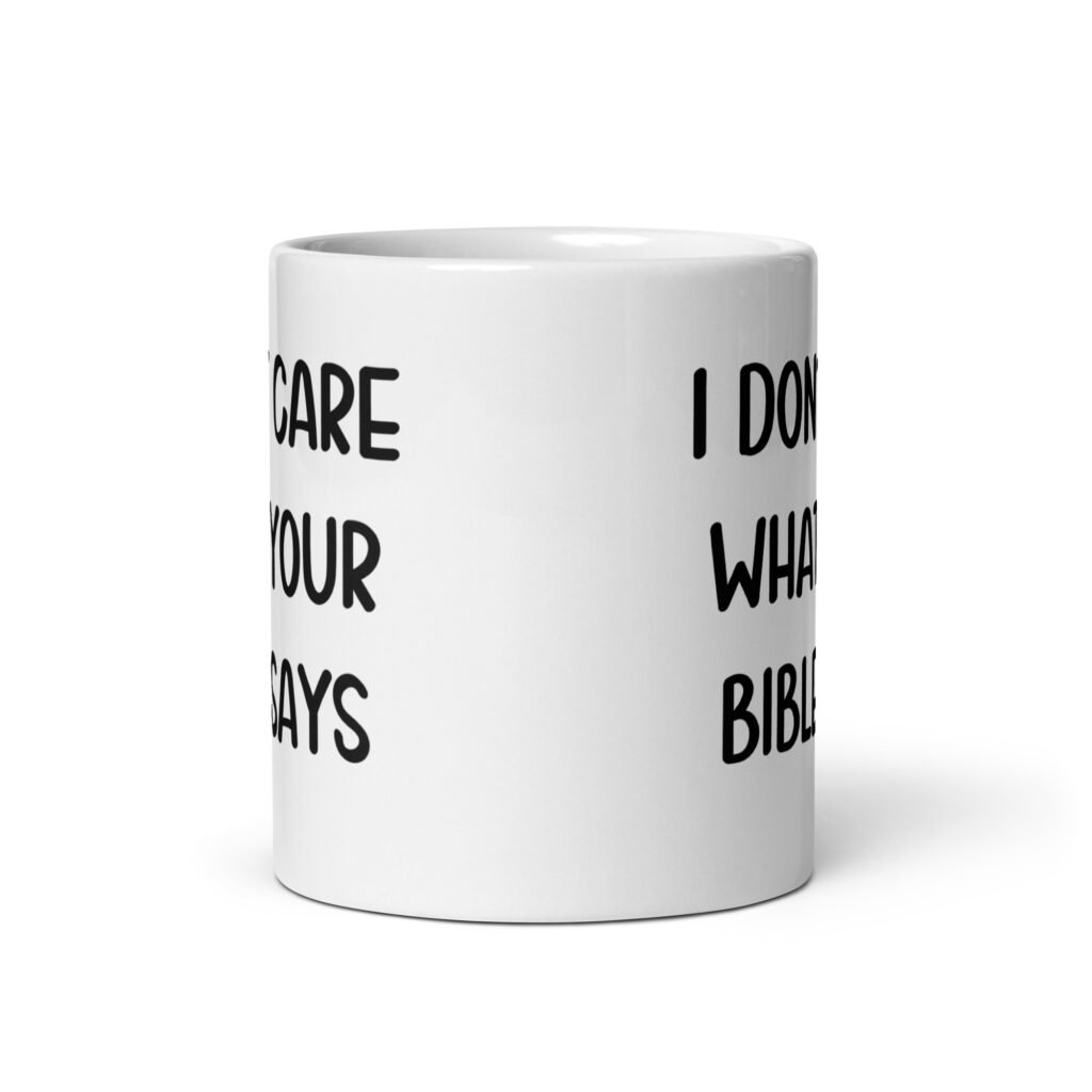 White ceramic coffee mug with the text 'I don't care what your bible says' printed on both sides.