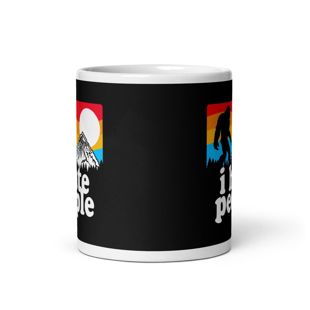 White coffee mug with graphic of Bigfoot walking into the sunset with the text 'I hate people' printed on both sides.