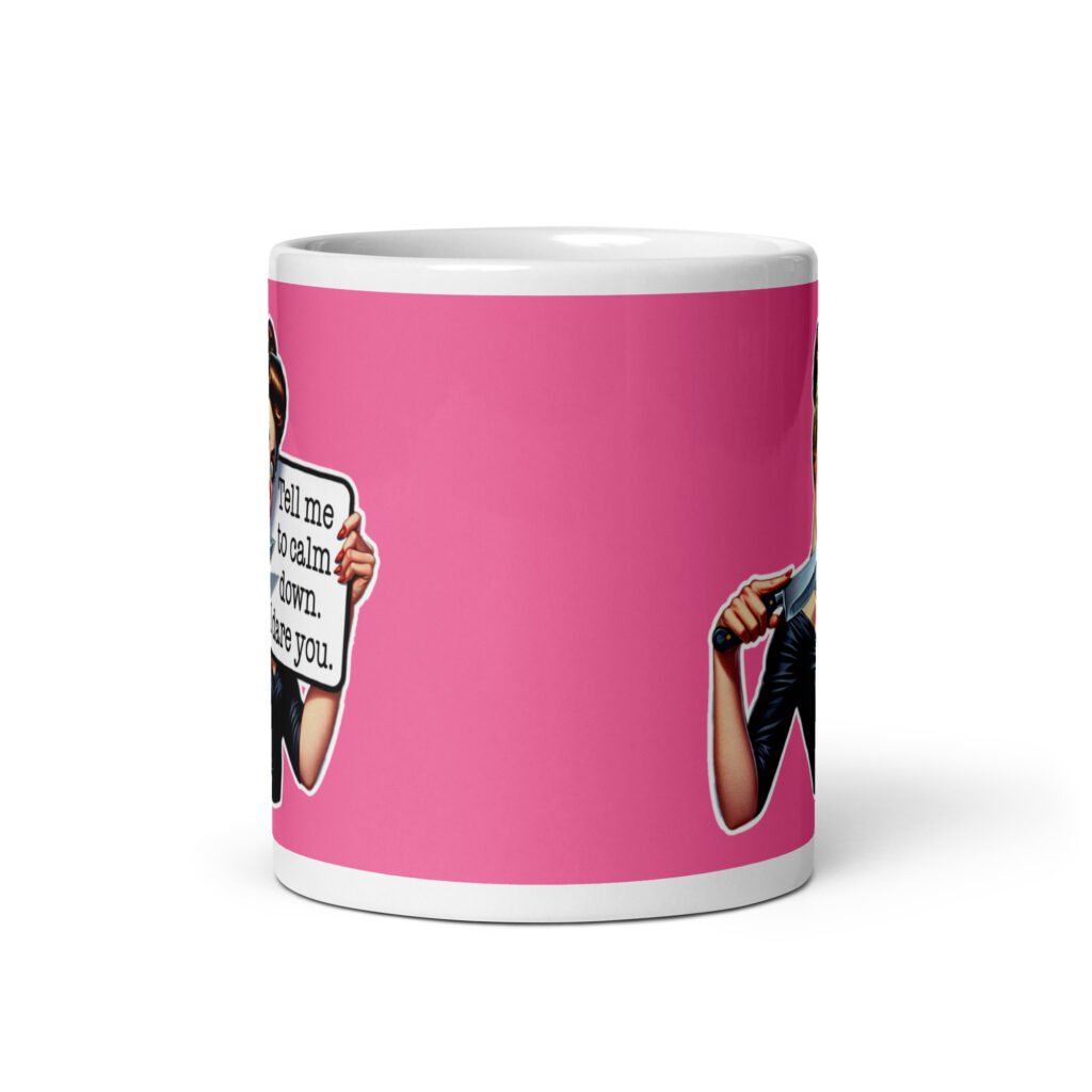 White ceramic coffee mug with pink color wrapped around. The mug has a graphic of an angry looking retro woman holding a knife and a sign. The sign says 'Tell me to calm down. I dare you.' The graphic is printed on both sides of the mug.