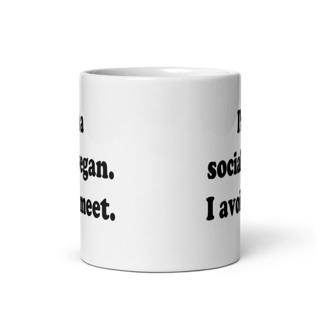 White ceramic mug with the pun phrase 'I'm a social vegan. I avoid meet.' printed on both sides.