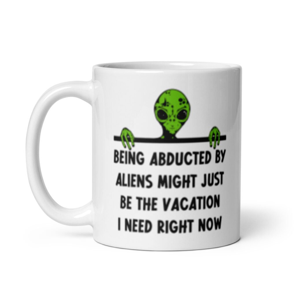 White ceramic mug with image of an alien and the words 'Being abducted by aliens might just be the vacation I need right now' printed on both sides.