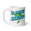 White ceramic mug with the phrase 'Blame is on the anxiety' printed on both sides of the mug. The graphics are bold and in aqua and lime green.
