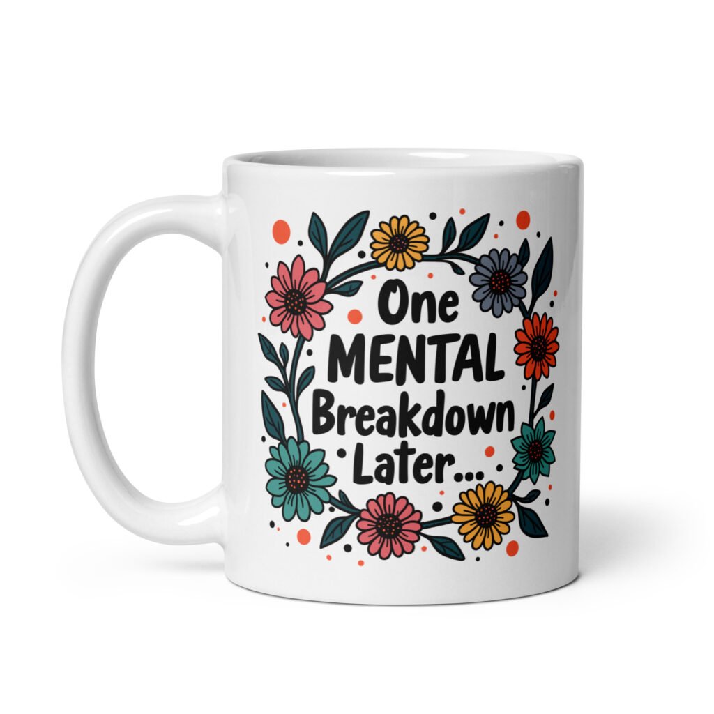 White ceramic mug with a multi color floral wreath design printed on both sides. The words 'One mental breakdown later...' are printed in the center of the wreath.