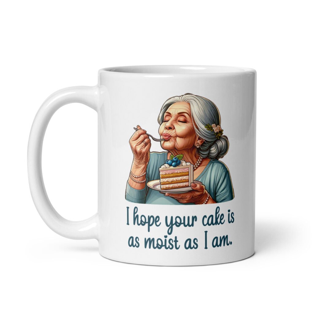 White ceramic coffee mug with an image of grey haired older woman enjoying a bite of a piece of cake with the words 'I hope your cake is as moist as I am' printed on both sides.