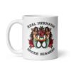 White ceramic mug with image of 2 mermaids and the text 'Real mermaids smoke seaweed' printed on both sides.