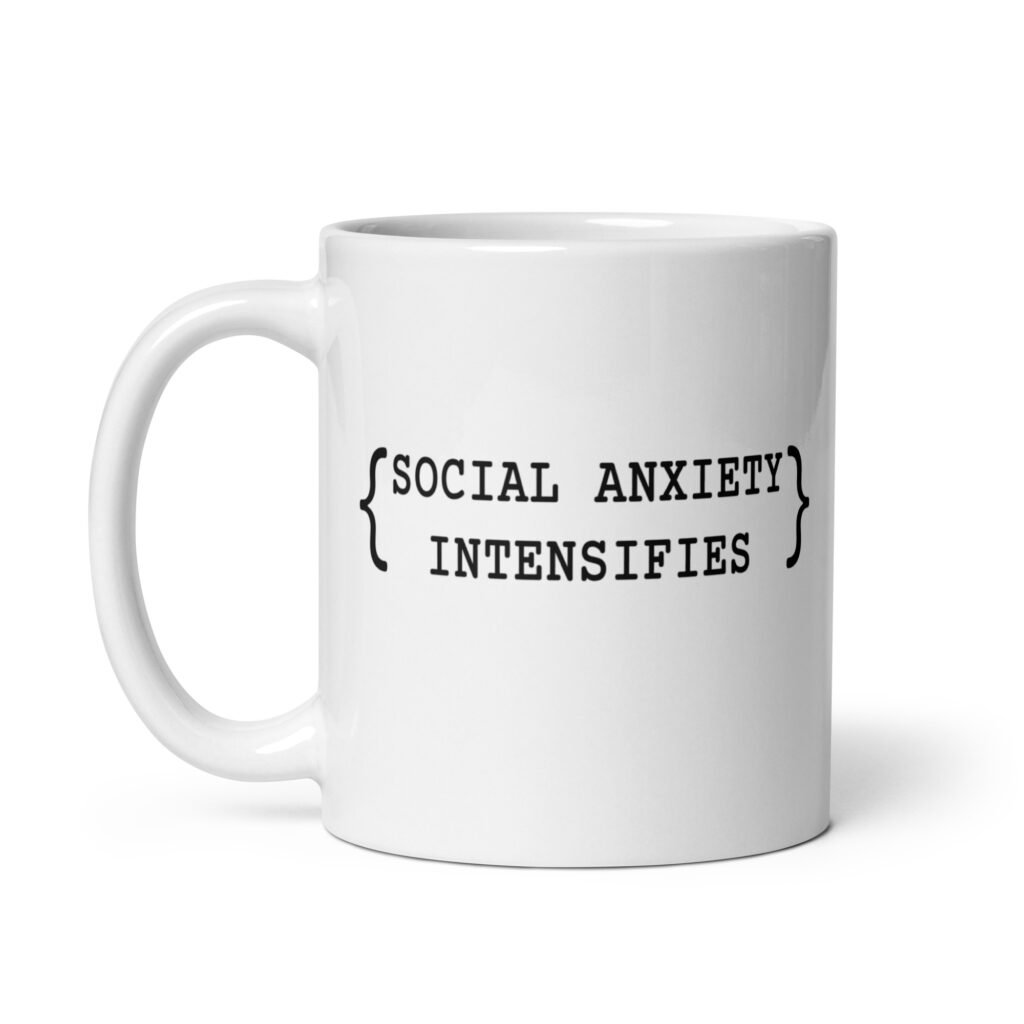 White ceramic coffee mug with the text 'Social anxiety intensifies' printed on both sides.