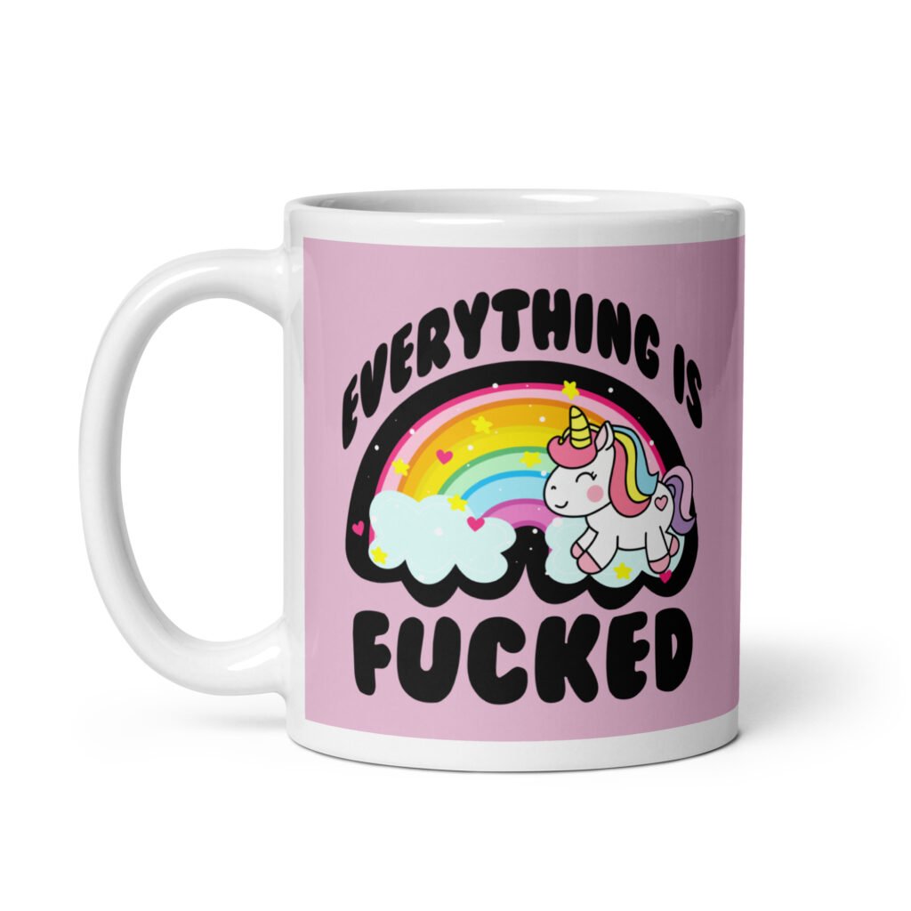 Pink and white ceramic coffee mug with a graphic of a kawaii style unicorn and a pastel rainbow with the text 'Everything is fucked' printed on both sides. The background is pink.