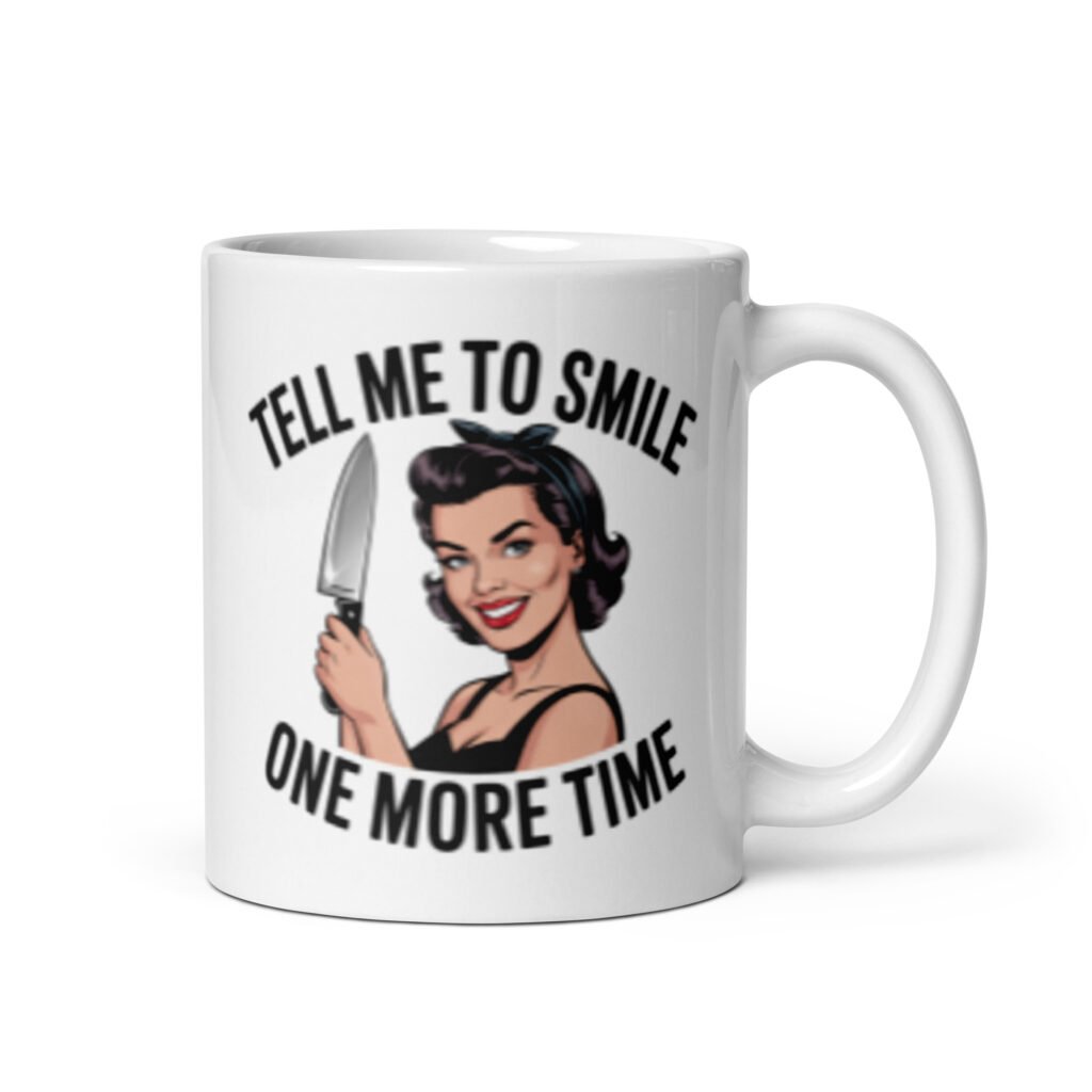 White ceramic mug with graphic of a woman holding a knife and the phrase 'Tell me to smile one more time' printed on both sides.