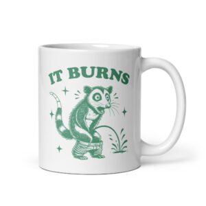 White ceramic mug with an image of an opossum peeing. The words 'It burns' are printed above.