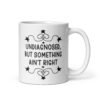 White ceramic mug with the text 'Undiagnosed, but something ain't right' printed on both sides.