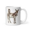 White ceramic coffee mug with an image of a donkey with wise owl sitting on it printed on both sides of the mug.