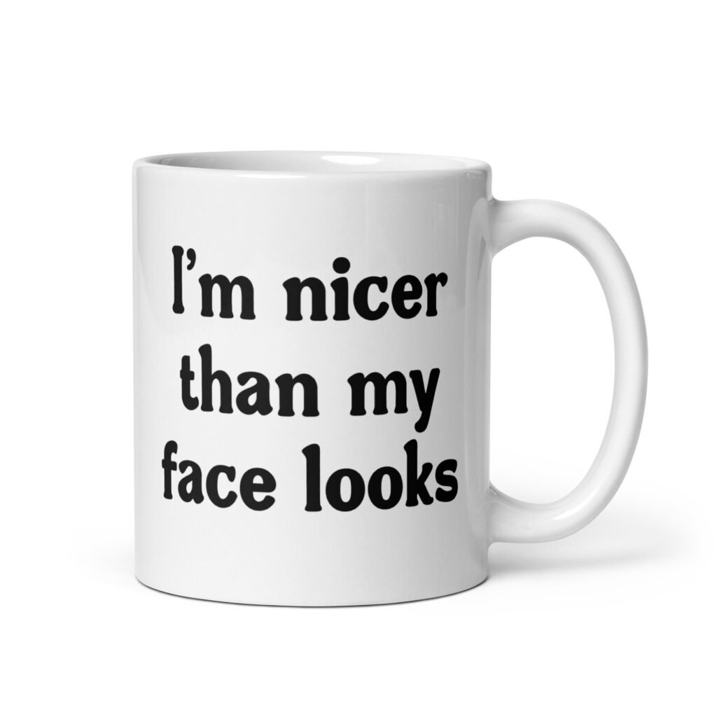 White ceramic coffee mug with the text 'I'm nicer than my face looks' printed on both sides.
