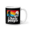 White coffee mug with graphic of Bigfoot walking into the sunset with the text 'I hate people' printed on both sides.