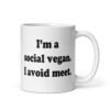 White ceramic mug with the pun phrase 'I'm a social vegan. I avoid meet.' printed on both sides.