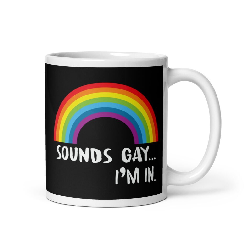Black and white ceramic coffee mug that has an image of a rainbow and the text 'Sounds gay... I'm in.' printed on both sides.