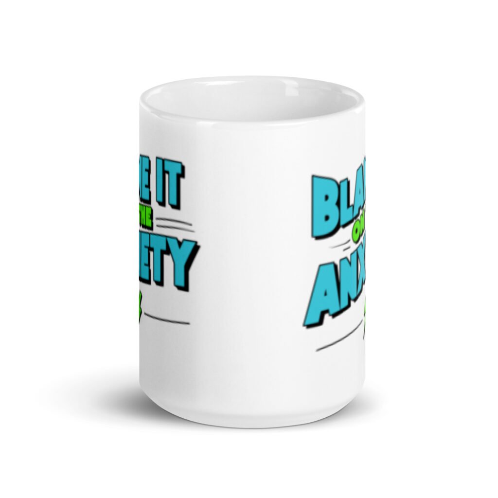 White ceramic mug with the phrase 'Blame is on the anxiety' printed on both sides of the mug. The graphics are bold and in aqua and lime green.