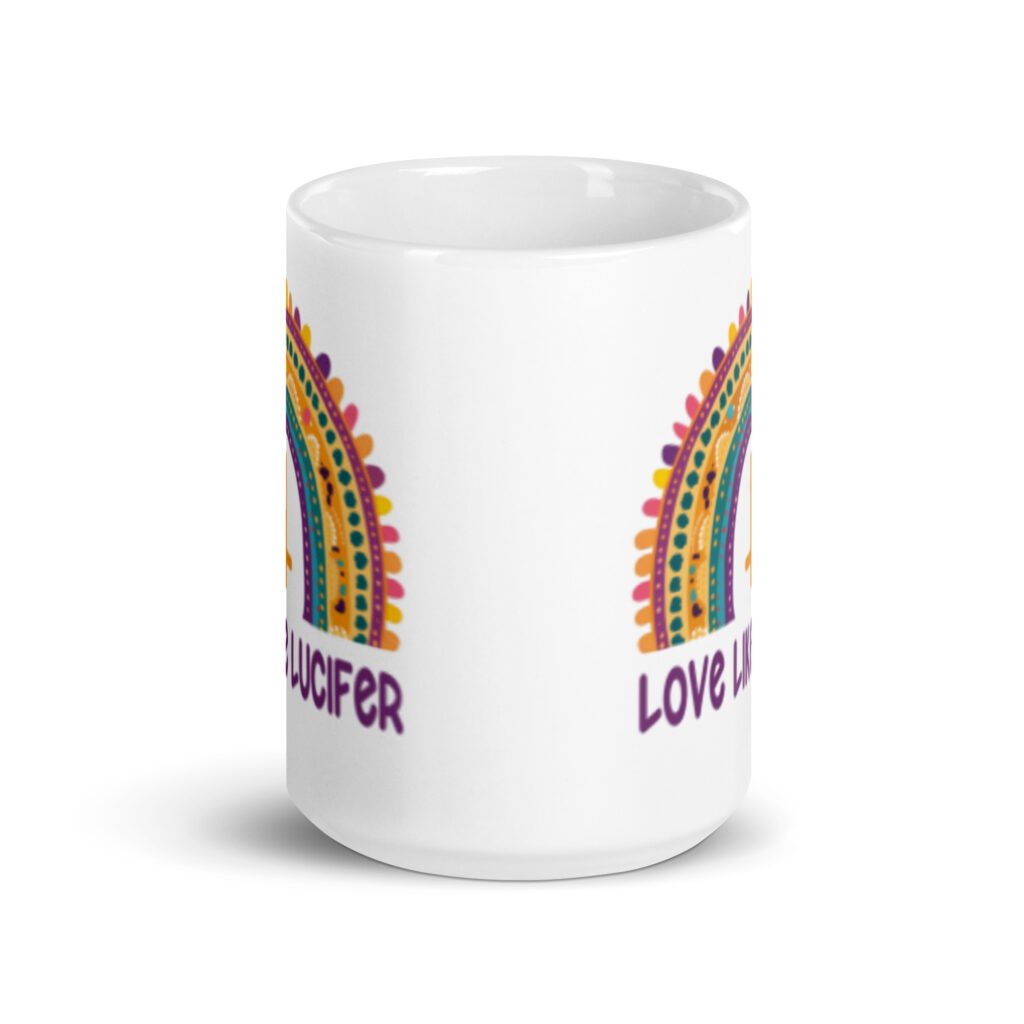 White ceramic mug with an image of a boho style rainbow. There is an upside down cross in the center arch of the rainbow and the text 'Love like Lucifer' printed under. The graphics are printed on both sides of the mug.