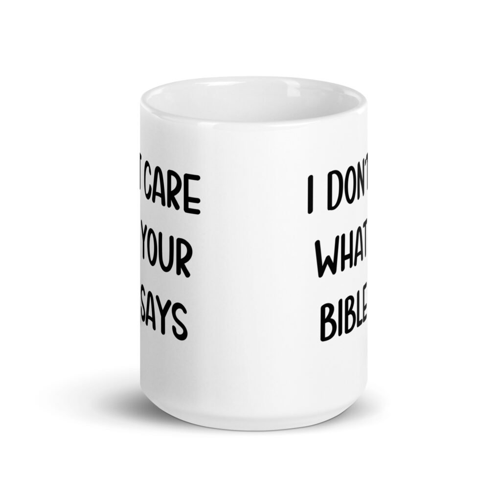 White ceramic coffee mug with the text 'I don't care what your bible says' printed on both sides.