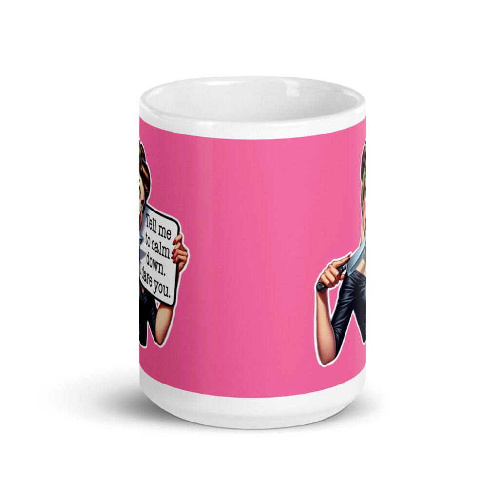 White ceramic coffee mug with pink color wrapped around. The mug has a graphic of an angry looking retro woman holding a knife and a sign. The sign says 'Tell me to calm down. I dare you.' The graphic is printed on both sides of the mug.