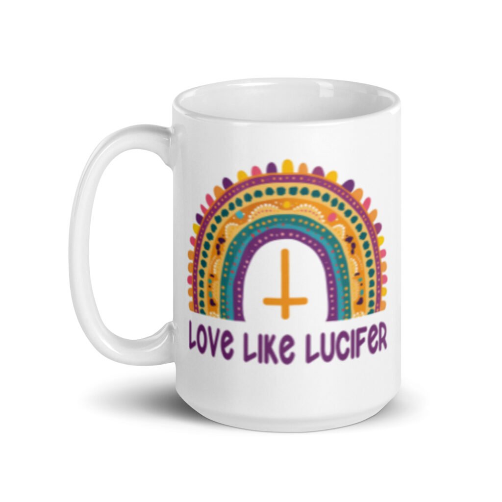 White ceramic mug with an image of a boho style rainbow. There is an upside down cross in the center arch of the rainbow and the text 'Love like Lucifer' printed under. The graphics are printed on both sides of the mug.