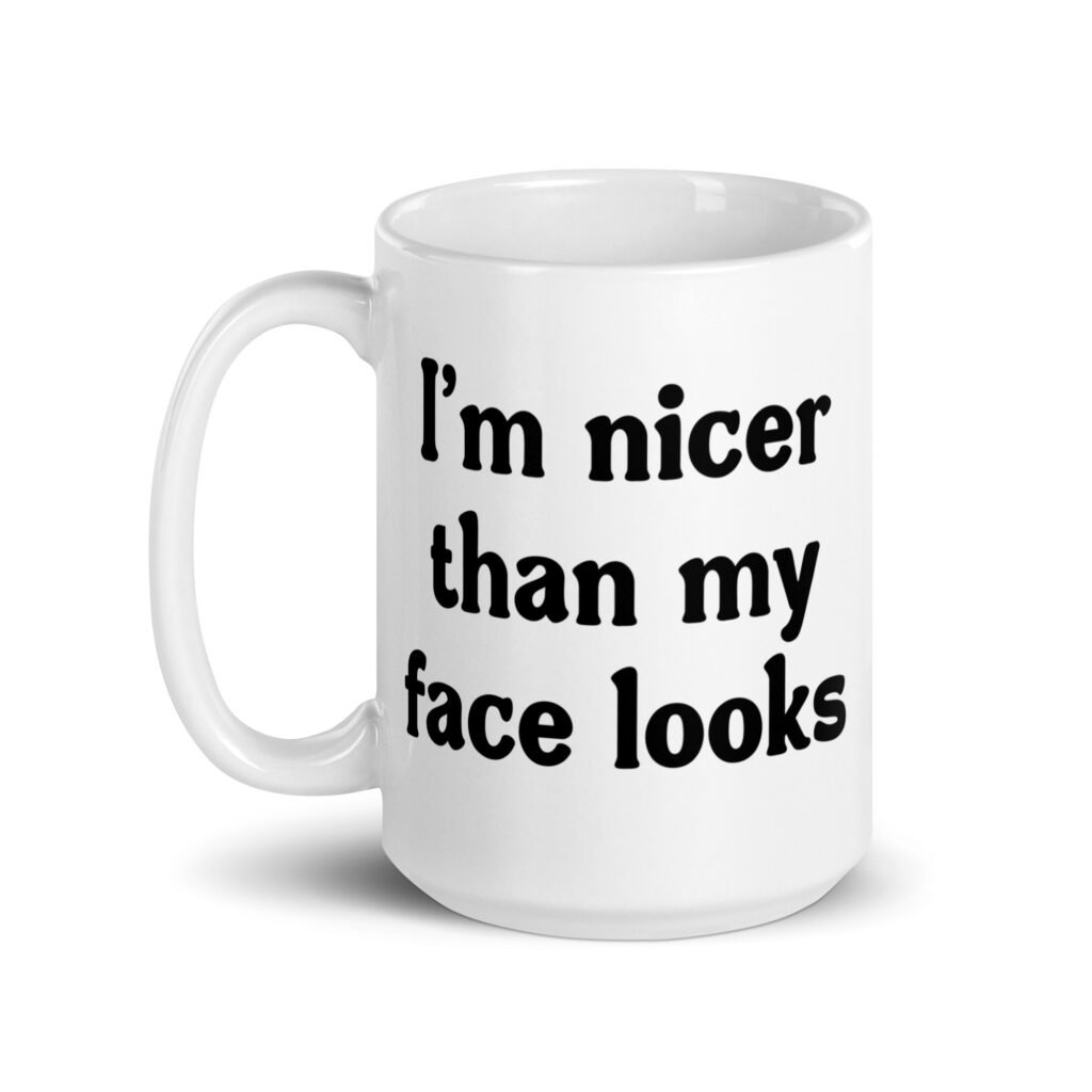 White ceramic coffee mug with the text 'I'm nicer than my face looks' printed on both sides.
