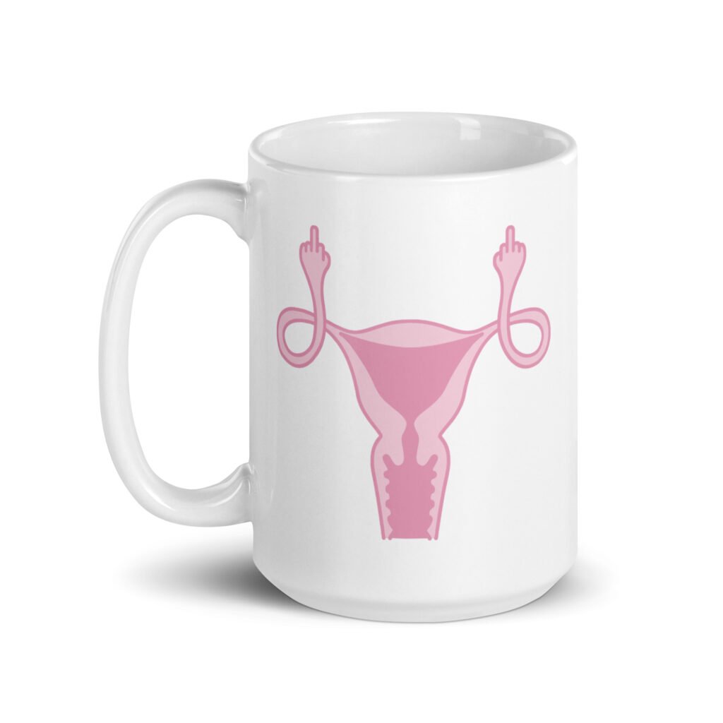 White ceramic coffee mug with with image of a pink uterus flipping middle finger graphic printed on both sides.