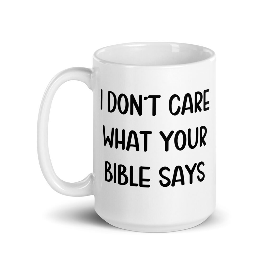 White ceramic coffee mug with the text 'I don't care what your bible says' printed on both sides.