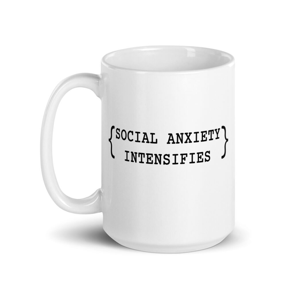 White ceramic coffee mug with the text 'Social anxiety intensifies' printed on both sides.