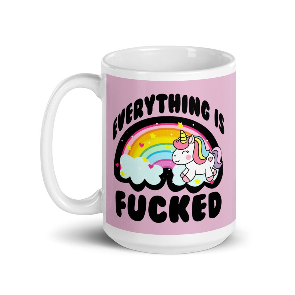 Pink and white ceramic coffee mug with a graphic of a kawaii style unicorn and a pastel rainbow with the text 'Everything is fucked' printed on both sides. The background is pink.