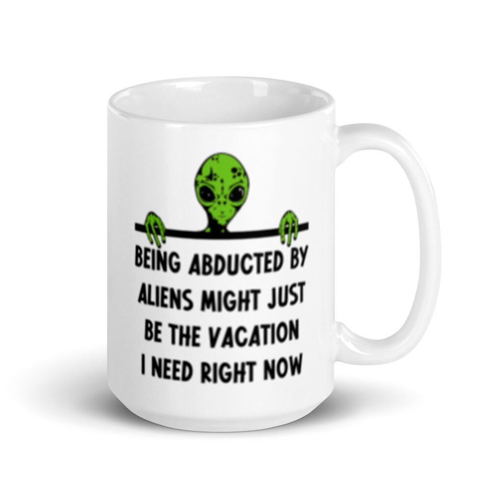 White ceramic mug with image of an alien and the words 'Being abducted by aliens might just be the vacation I need right now' printed on both sides.
