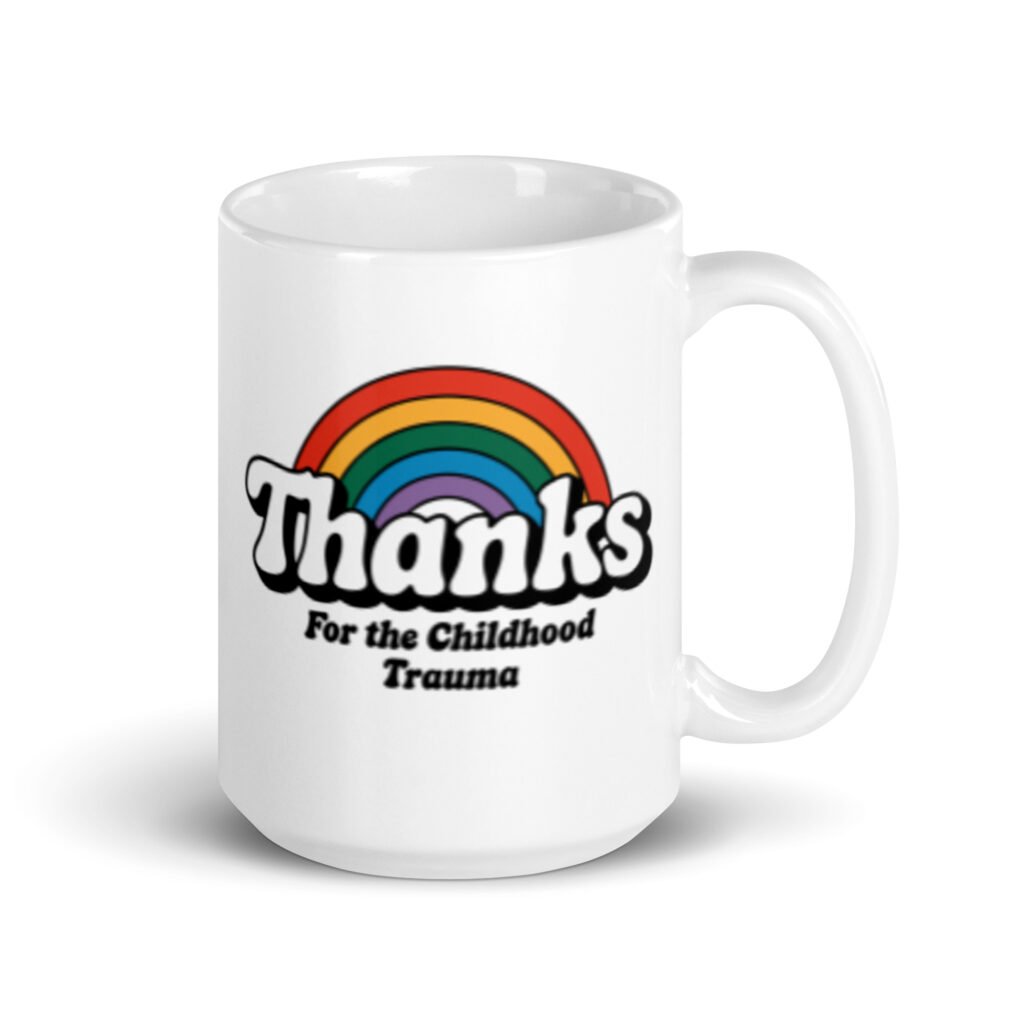 White ceramic mug with an image of a rainbow and the words 'Thanks for the childhood trauma' printed on both sides. The word Thanks is large and the rest of the words are smaller under.