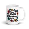 White ceramic mug with a multi color floral wreath design printed on both sides. The words 'One mental breakdown later...' are printed in the center of the wreath.