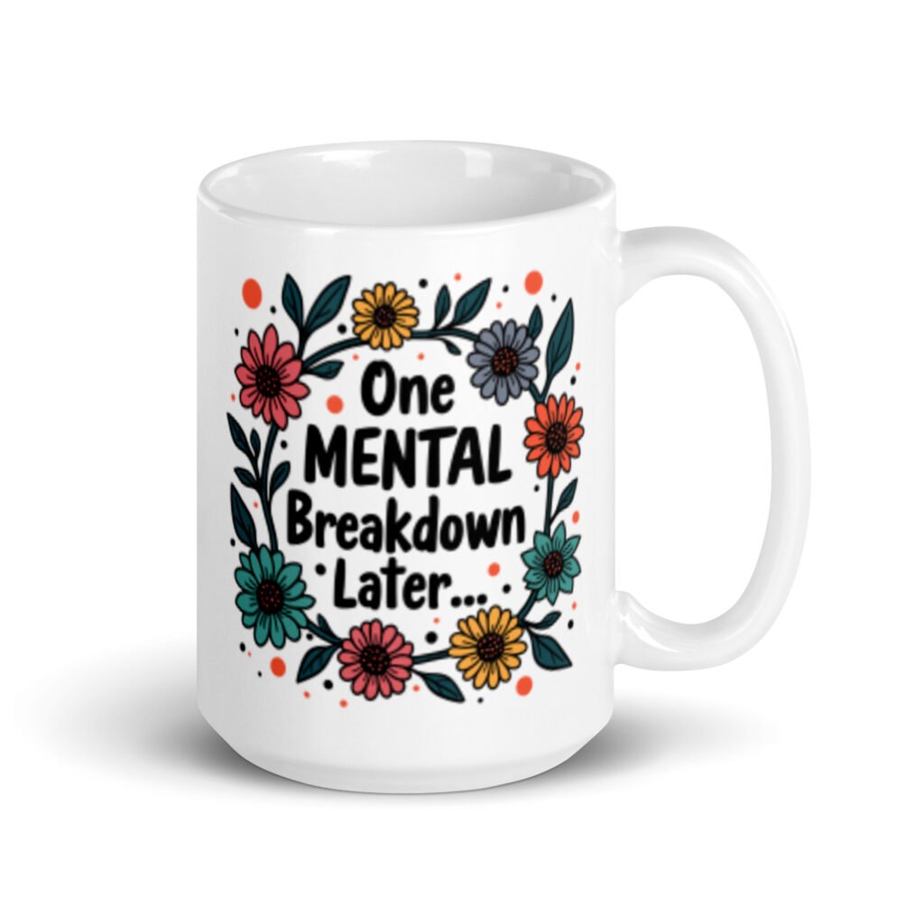 White ceramic mug with a multi color floral wreath design printed on both sides. The words 'One mental breakdown later...' are printed in the center of the wreath.