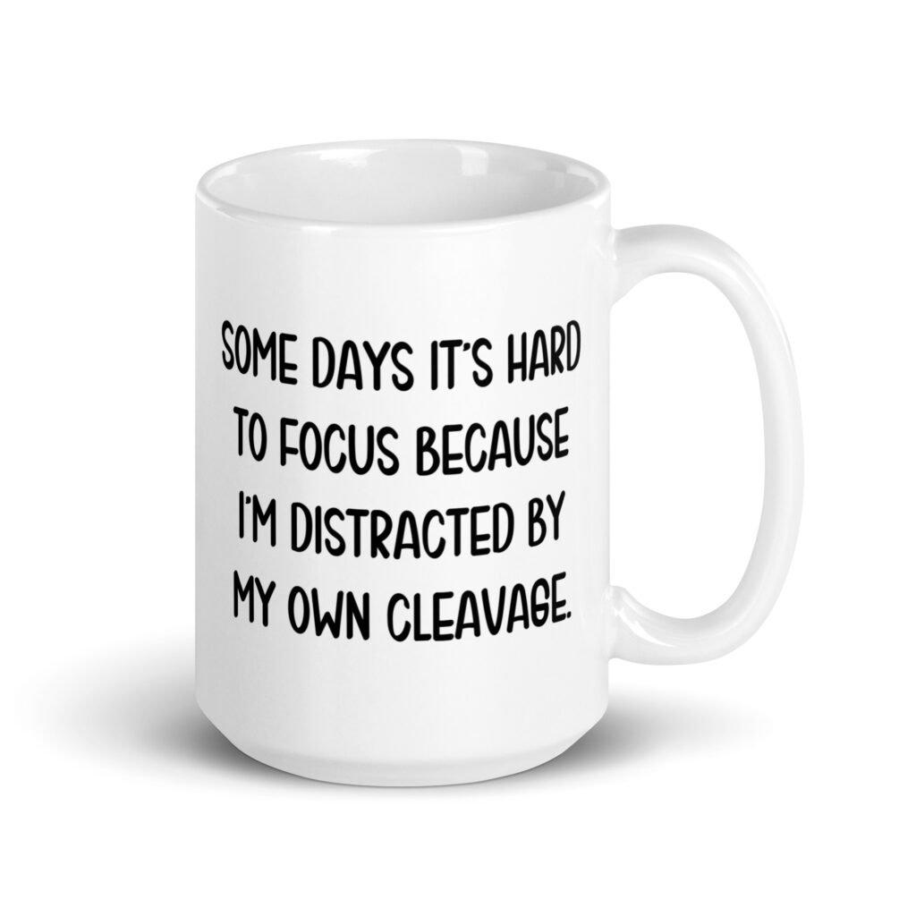 White ceramic mug with the phrase 'Some days it's hard to focus because I'm distracted by my own cleavage' printed on both sides.